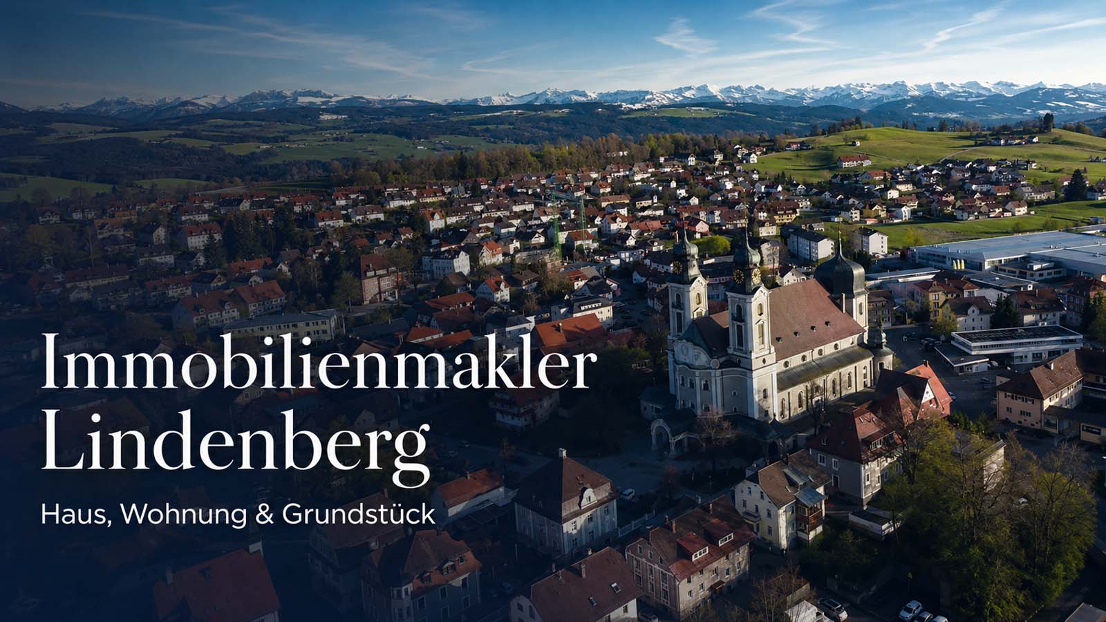 Lindenberg im Allgäu aus der Luft mit Kirche, Stadtansicht und Alpenpanorama als Beitragsbild für Immobilienmakler Lindenberg.