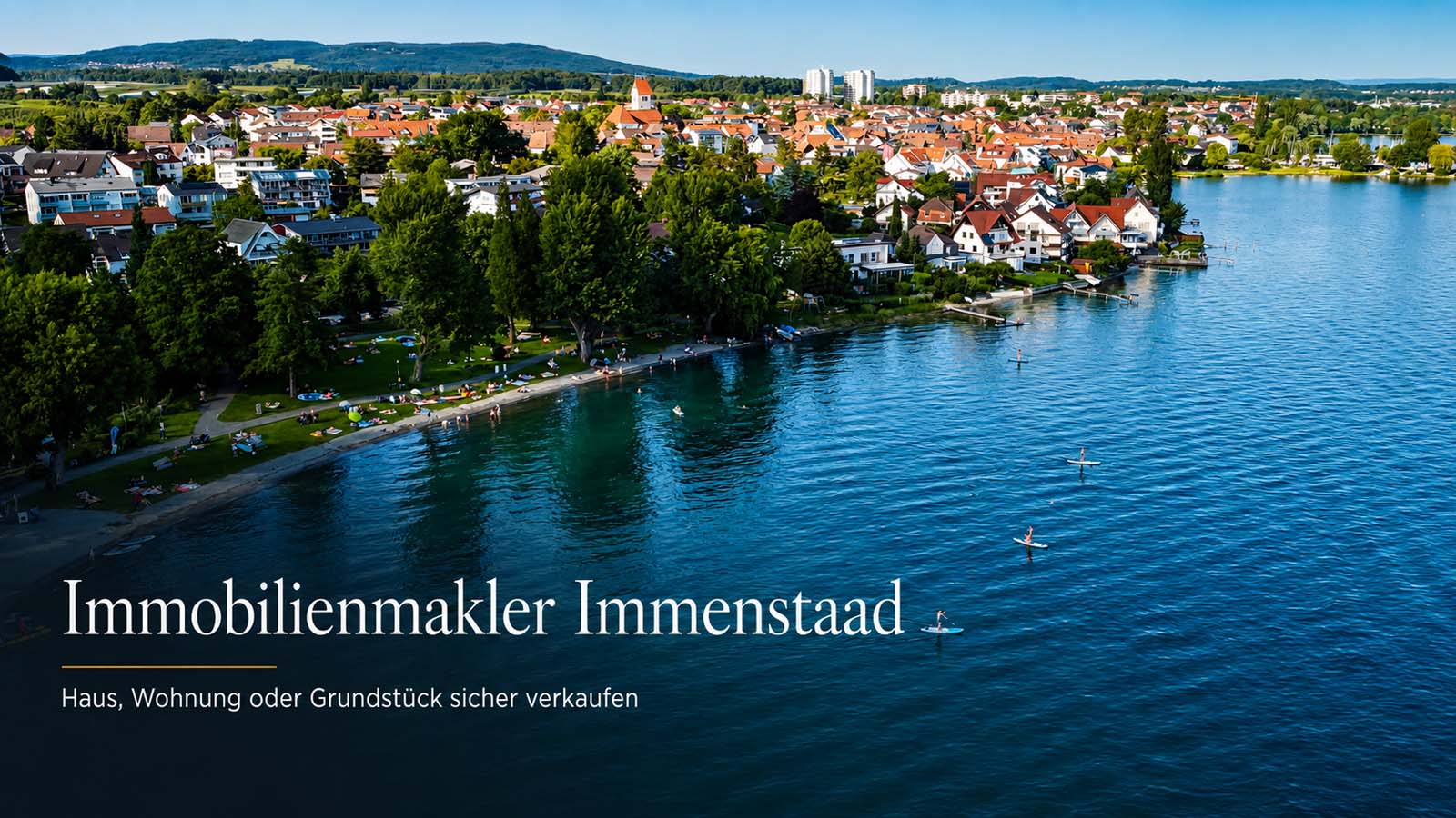 Luftaufnahme von Immenstaad am Bodensee mit Ufer, Wohnhäusern und dem Schriftzug „Immobilienmakler Immenstaad“